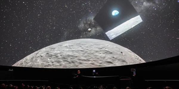 In the Planetarium at We The Curious with people in the audience looking up at the Moon and the image of 'Earthrise' the precursor to the Artemis 2 mission's 'Earthset'.