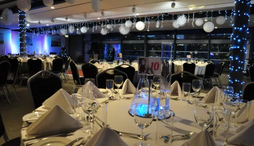 A room filled with round dining tables, adorned with Christmas decorations