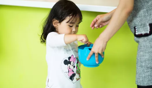 A young child stirs a mixture in a mixing bowl 