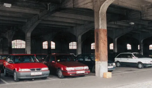 Old fashioned 1960s cars parked in a stone arched building