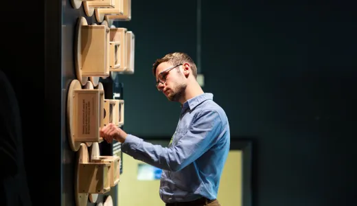 A person curiously  looking at a wall of sand clocks in the time exhibit 