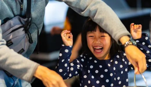 A child looking ecstatic while a grown-up next to them is making a giant bubble