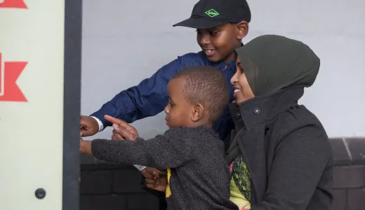 A family of three smile while interacting with an exhibit