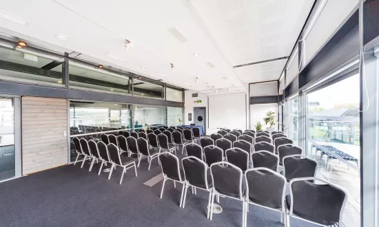 A long room filled with chairs arranged in rows facing away from the camera