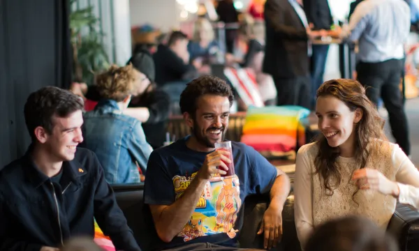 A group of people laughing around the table at a busy looking event