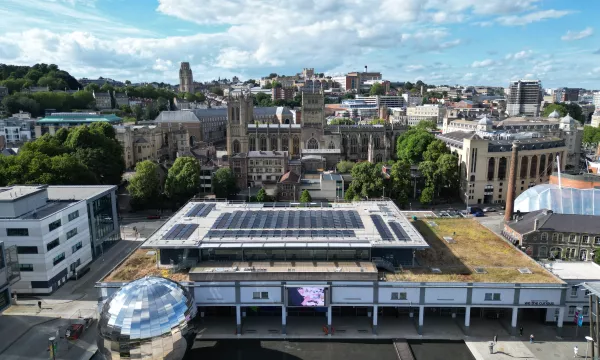 An aerial shot showing the We The Curious building, with solar panels on the roof. The silver Planetarium and Cathedral are either side of the main building. 