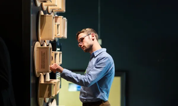 A person curiously  looking at a wall of sand clocks in the time exhibit 