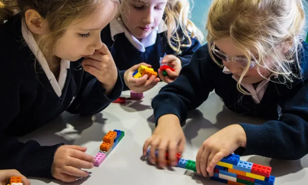 3 children build walls with small coloured bricks