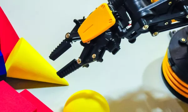 a yellow and black robotic arm next to some foam shapes