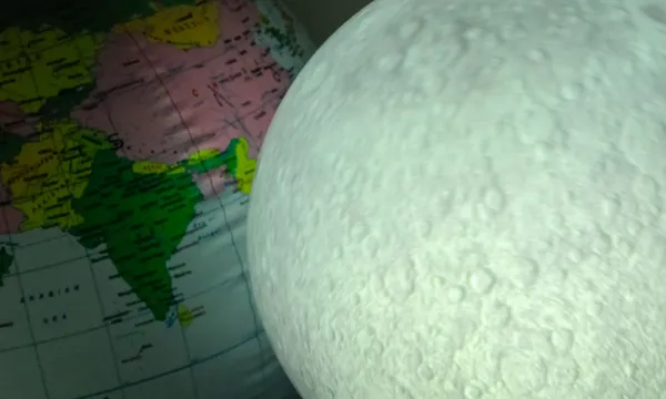 Lit up inflatable moon, next to an inflatable Earth