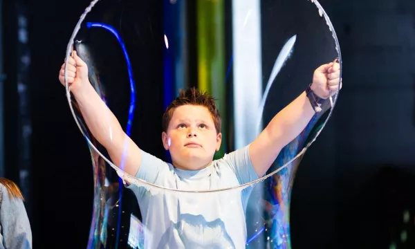 A child pulling a giant bubble over their head