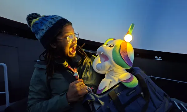 Member of staff making a very excited face with an alien puppet that has lights on it's head