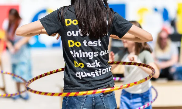 A We The Curious staff member facing away from camera, hula hooping with some children. 