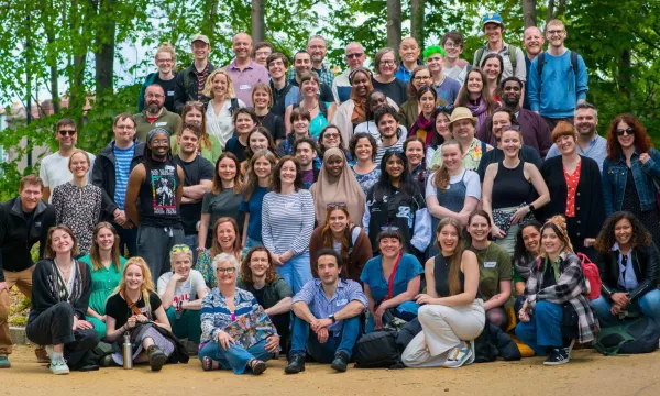 A big group of most of the We The Curious staff, volunteers and trustees standing and smiling towards the camera in a green space