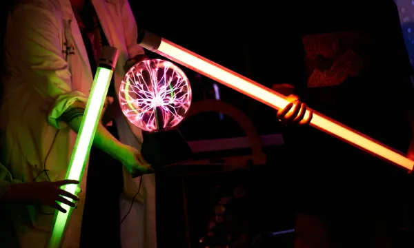 There are two light up rods touching a plasma ball in the centre of the image