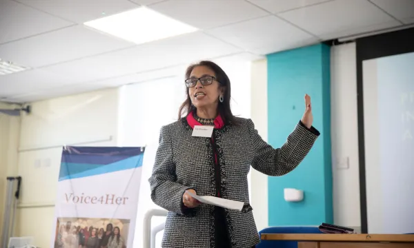 A person in a black and white blazer making a speech