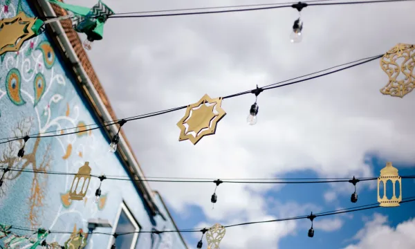 Golden Eid decorations hang from string lights strung between buildings