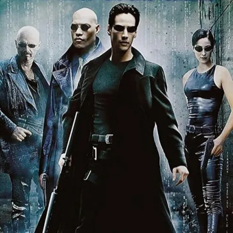 A poster for the film The Matrix. There are 4 people stood in a row, cut from different scenes, wearing black with dark sunglasses.