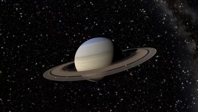 Saturn and its rings in front of a dark night sky with stars.