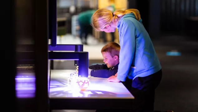 A child and an adult excitedly exploring an exhibit with light and shadows