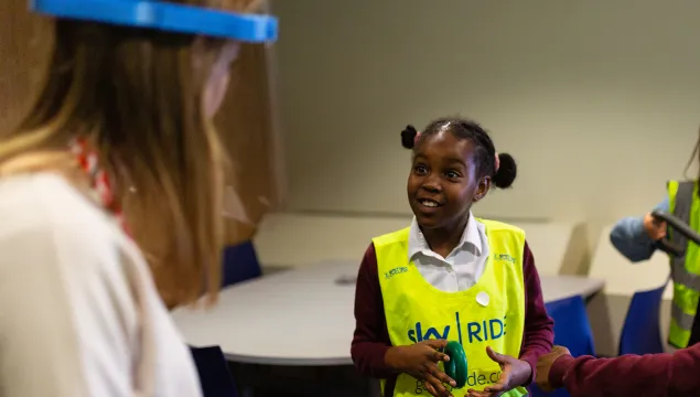 A girl smiling and interacting with a member of staff in a classroom environment