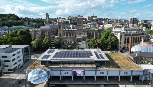 An aerial shot showing the We The Curious building, with solar panels on the roof. The silver Planetarium and Cathedral are either side of the main building. 