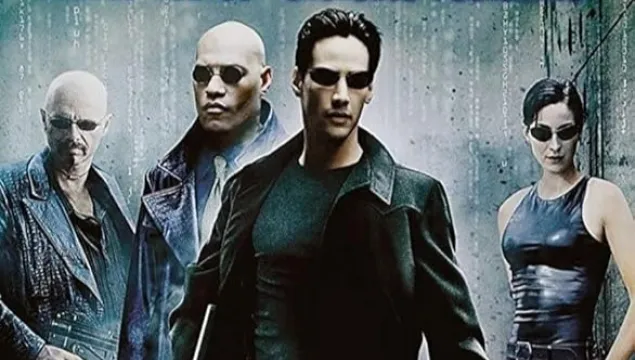 A poster for the film The Matrix. There are 4 people stood in a row, cut from different scenes, wearing black with dark sunglasses.