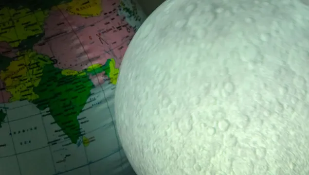 Lit up inflatable moon, next to an inflatable Earth