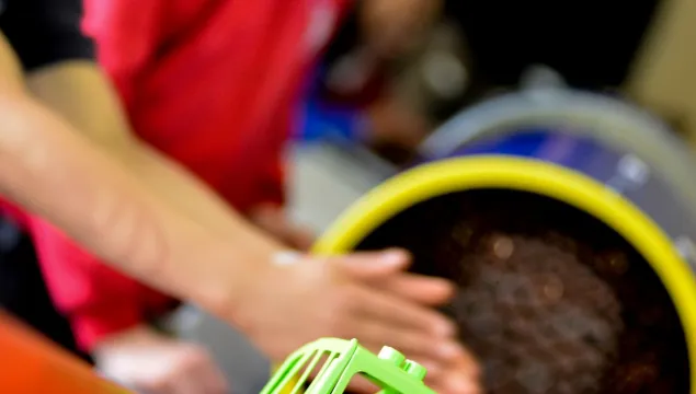 a green truck in the foreground, with 2 children and a fan in the background