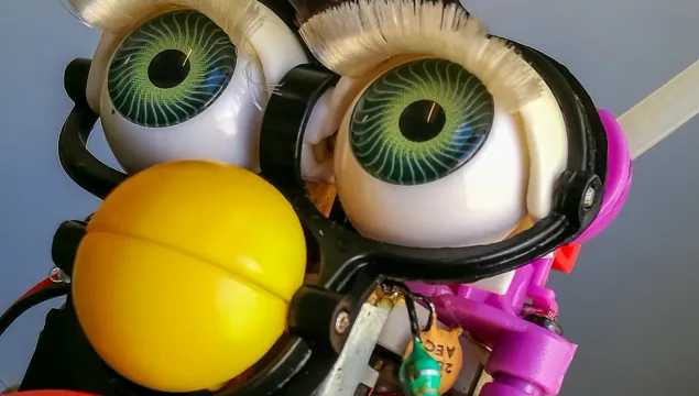 a close up picture of the eyes and yellow beak of a mechanical child's toy (Furby))