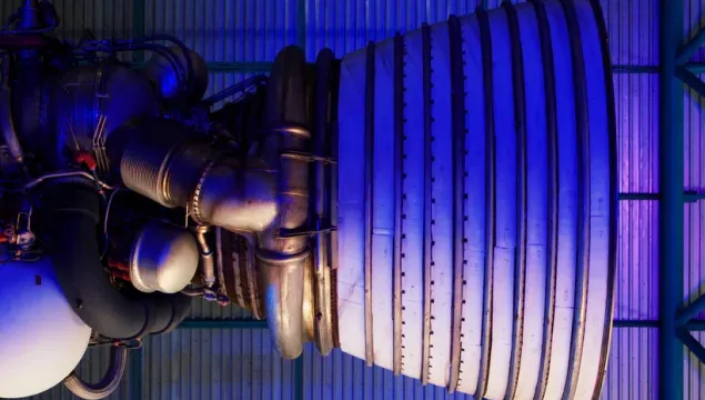 A close up of a rocket fuel burner on it's side, lit with blue lighting