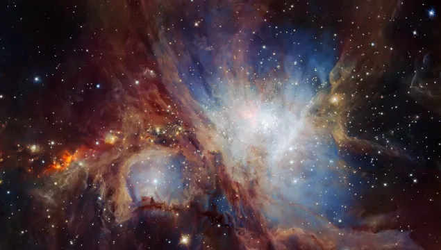 The Orion Nebula. A black background with clouds of blue, red and white, and some stars.