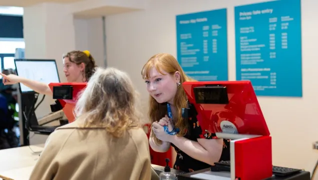 A member of We The Curious staff talks to a visitor at the Welcome Desk