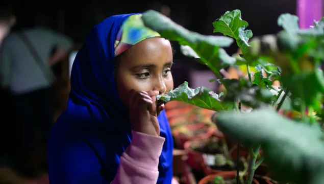 A child smelling a plant blissfully 