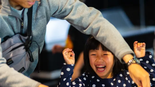 A child looking ecstatic while a grown-up next to them is making a giant bubble