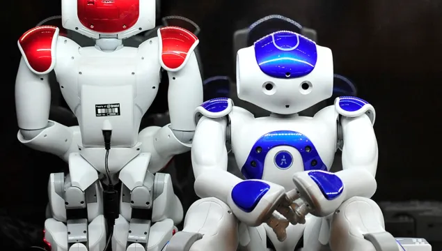 Two Noa robots - small white humanoid form with read and blue colouring