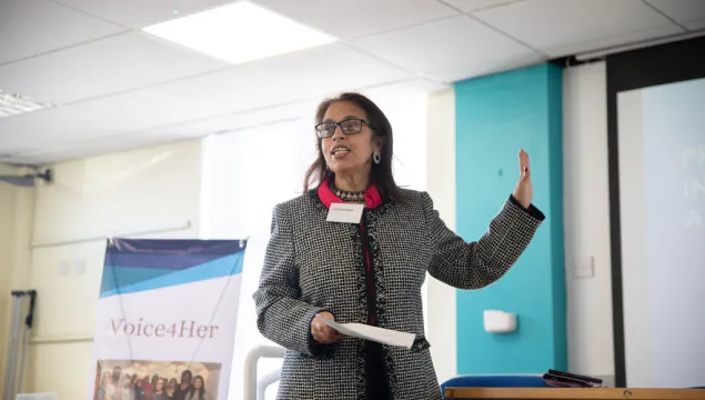 A person in a black and white blazer making a speech