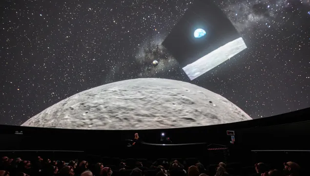 In the Planetarium at We The Curious with people in the audience looking up at the Moon and the image of 'Earthrise' the precursor to the Artemis 2 mission's 'Earthset'.