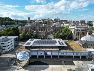 An aerial shot showing the We The Curious building, with solar panels on the roof. The silver Planetarium and Cathedral are either side of the main building. 