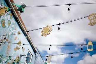 Golden Eid decorations hang from string lights strung between buildings