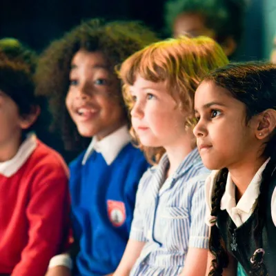 A group of four primary school aged children sat on a bench, all watching a live science show. Credit Julian Welsh