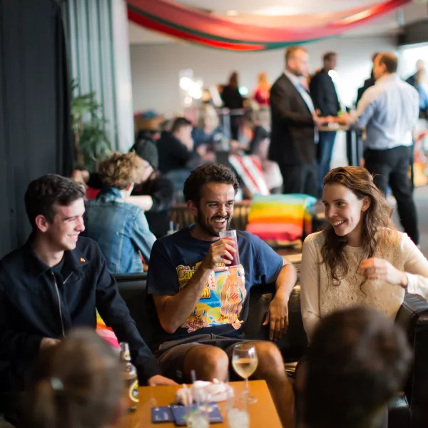 A group of young adults sat down, drinking and smiling together