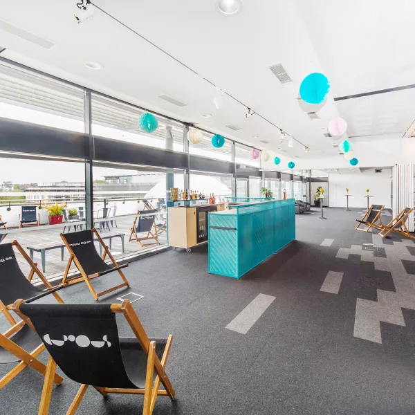 A room with deck chairs and a Teal bar. Festoons are hanging from the ceiling