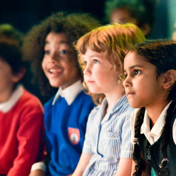 A group of 4 primary school children - looking off camera to the left, some concentrating, some smiling. 