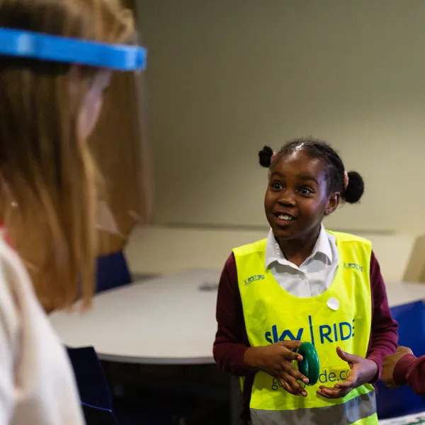 A girl smiling and interacting with a member of staff in a classroom environment