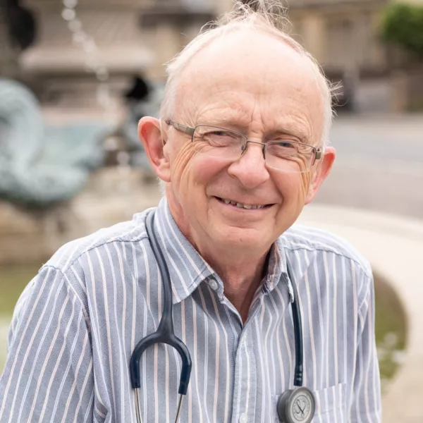 We The Curious volunteer Dr Chris Fox smiling at the camera standing in front of a water feature 