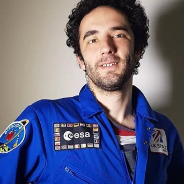 We The Curious volunteer smiling at the camera wearing an astronaut outfit with ESA logo at the front