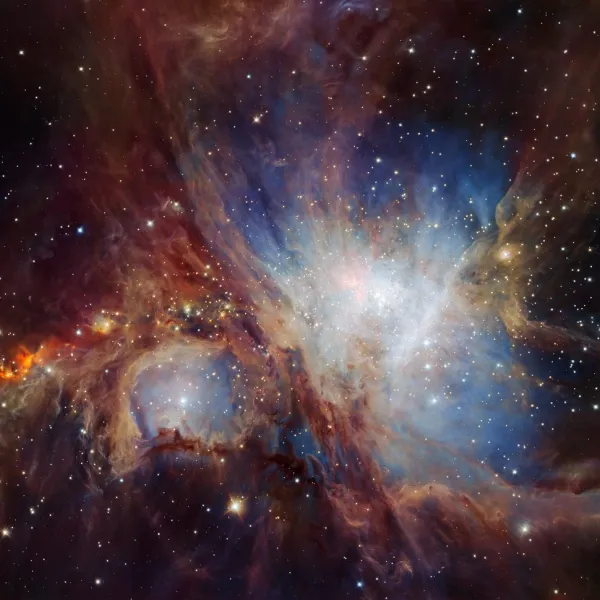 The Orion Nebula. A black background with clouds of blue, red and white, and some stars.