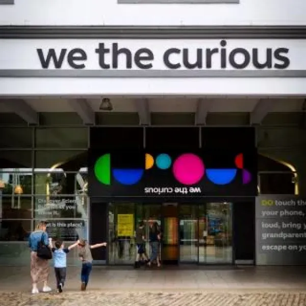 Front doors of We The Curious opening with a family looking excited to go in