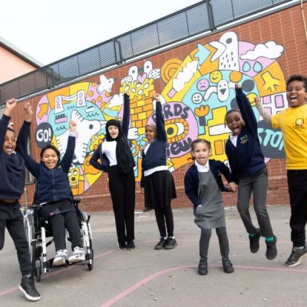 Hannah More school pupils and their headteacher stood in front of a colourful mural. Image credit Freia Turland